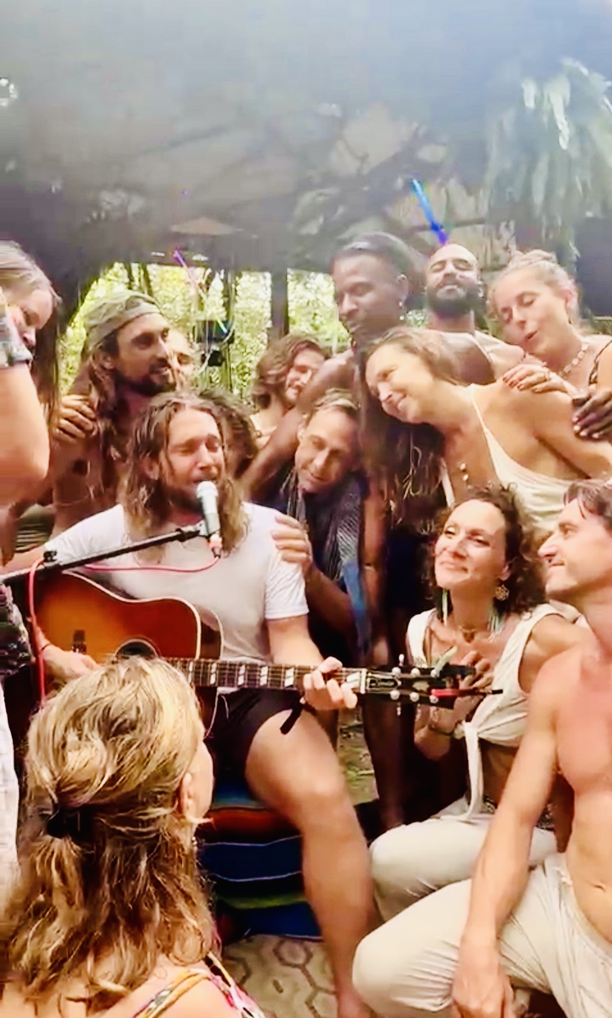 Drew sharing music with people gathered closely around him