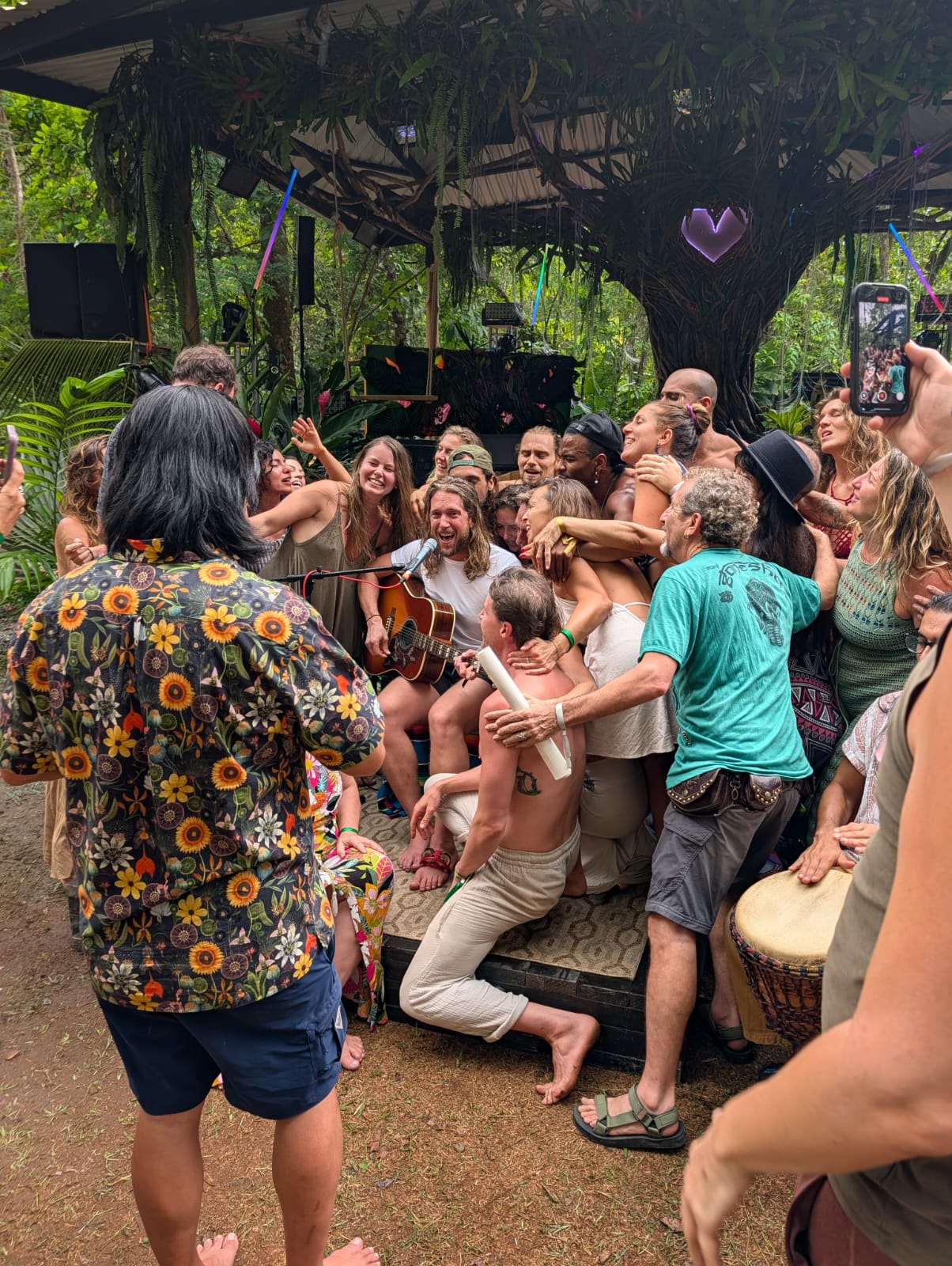 Drew playing guitar among a circle of people singing outdoors
